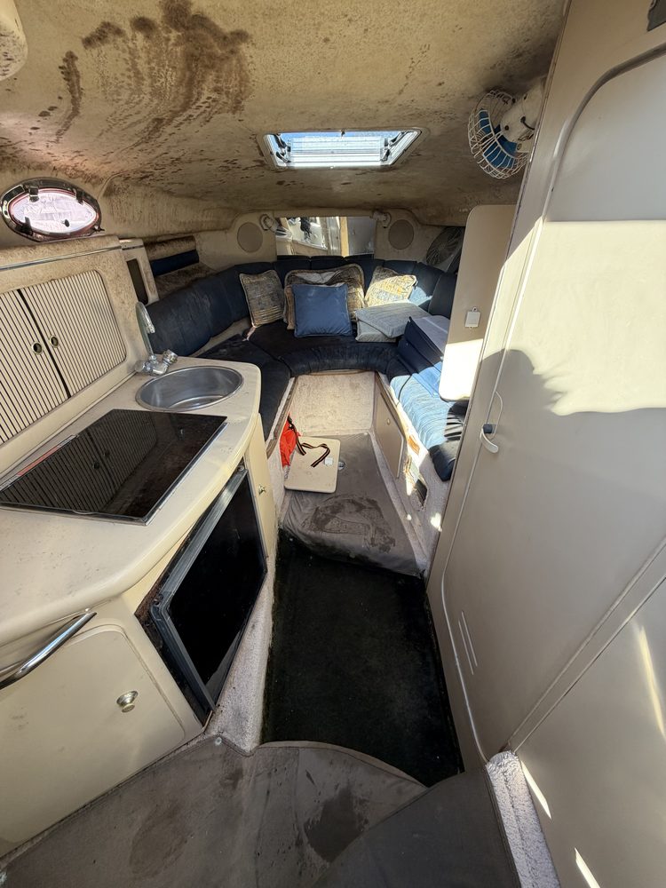 A cuddy cabin with a handprint on the ceiling, stained carpet and dirty cushions