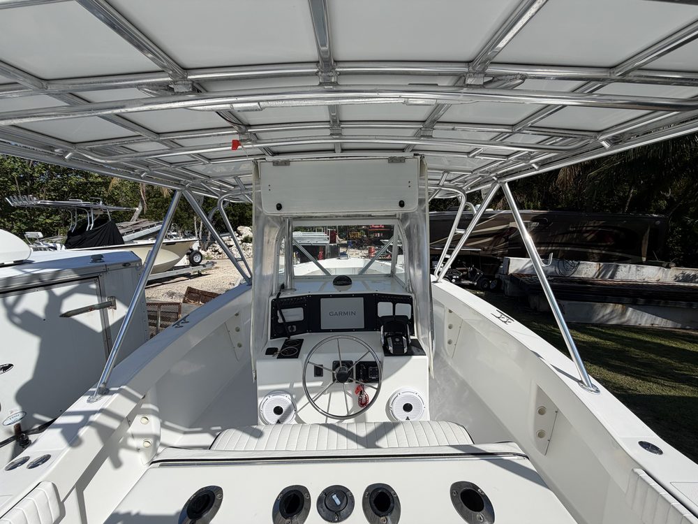 The helm of an offshore center console under a tower