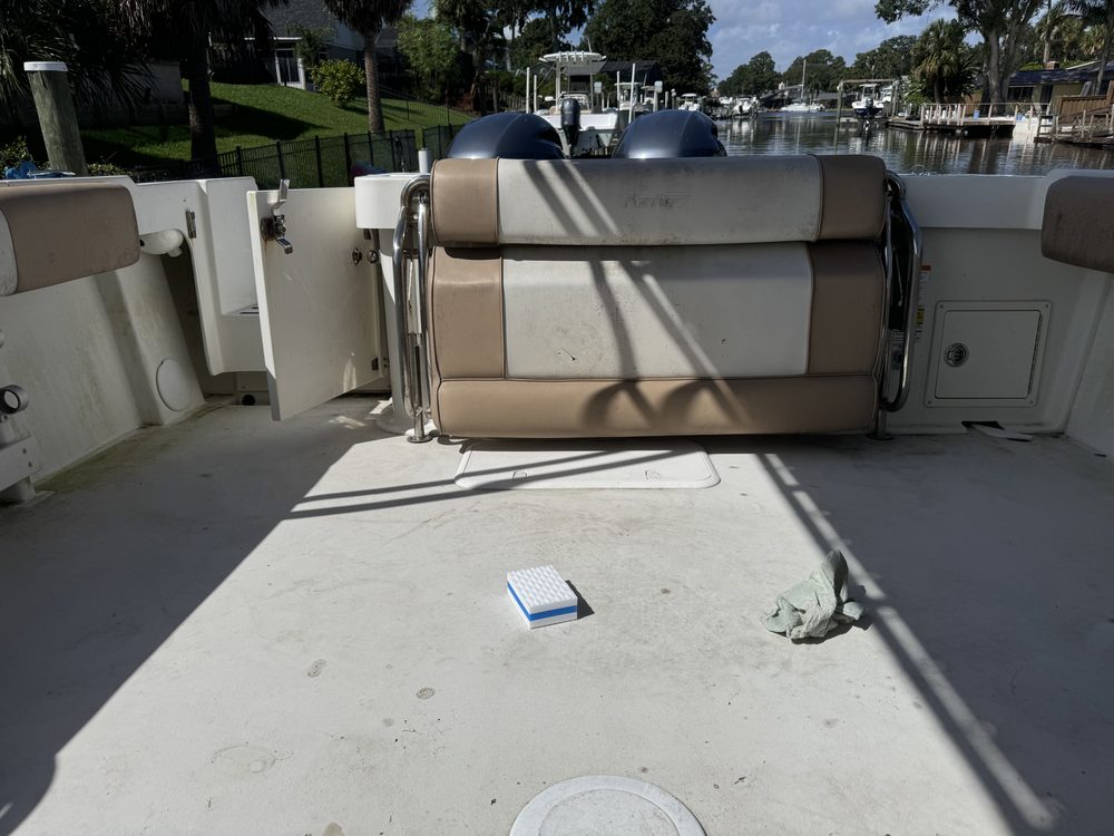 A cockpit and stern seat before cleaning, with a sponge on the deck