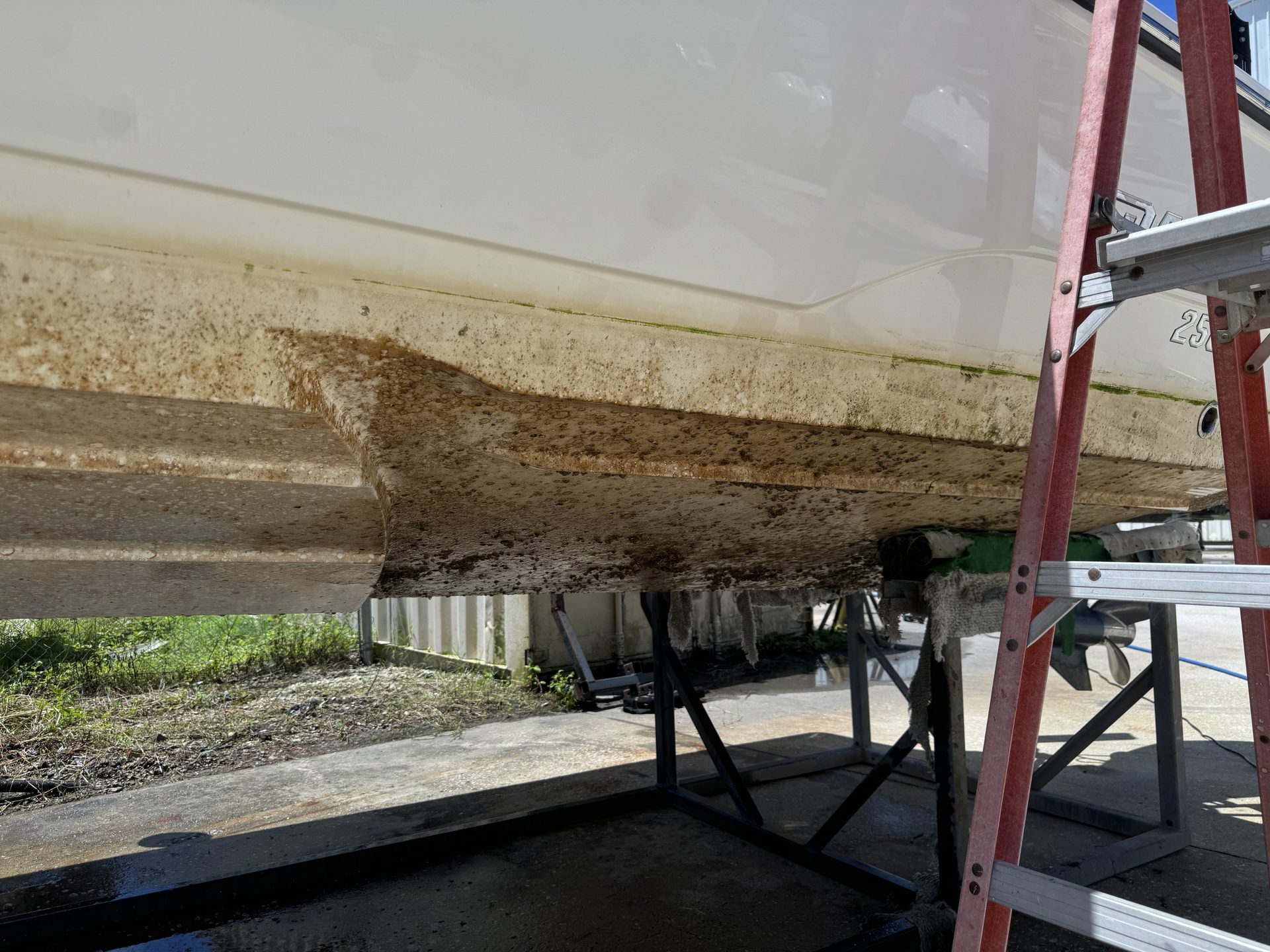Heavy staining along a hull bottom before work, on stands