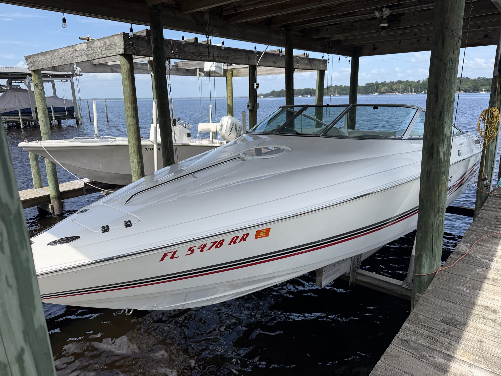 A cuddy boat on a lift beside a dock on the river